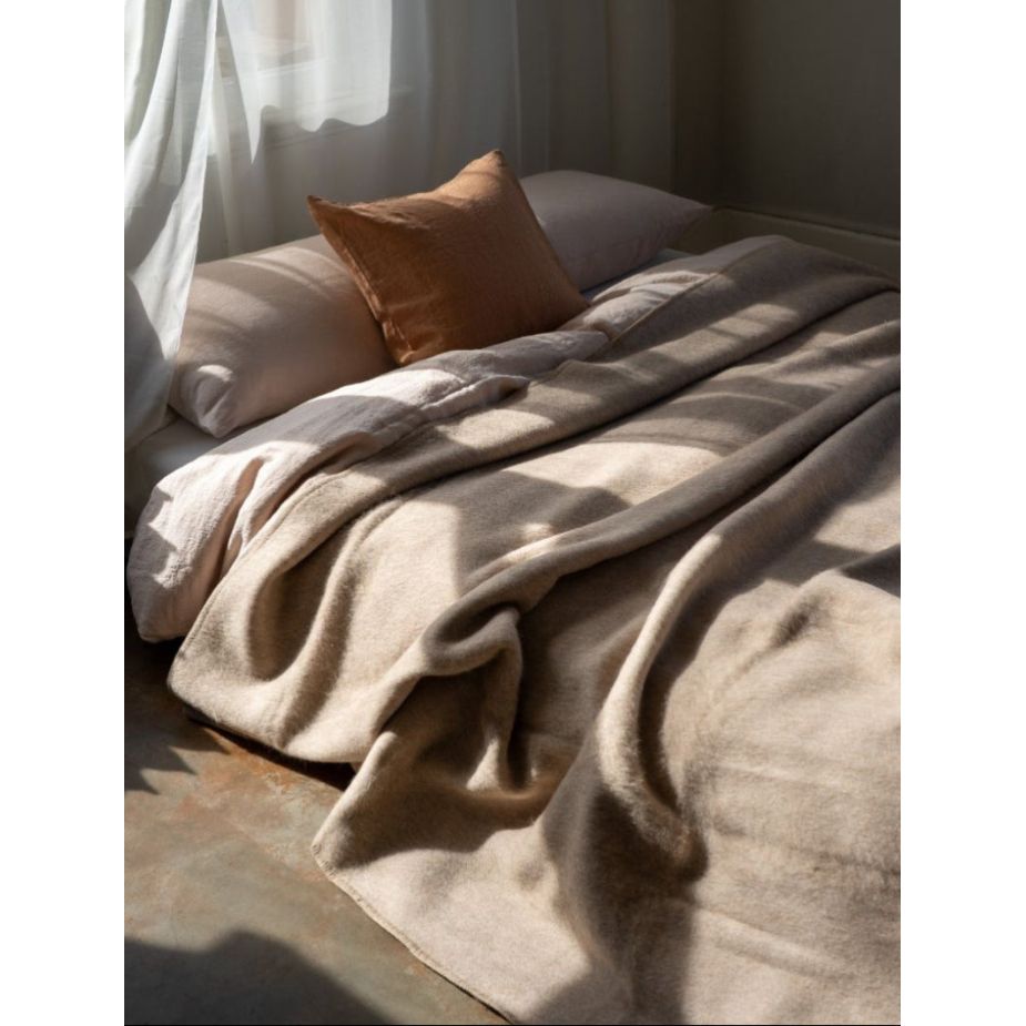 Cozy bed with beige blanket and pillow in a softly lit room
