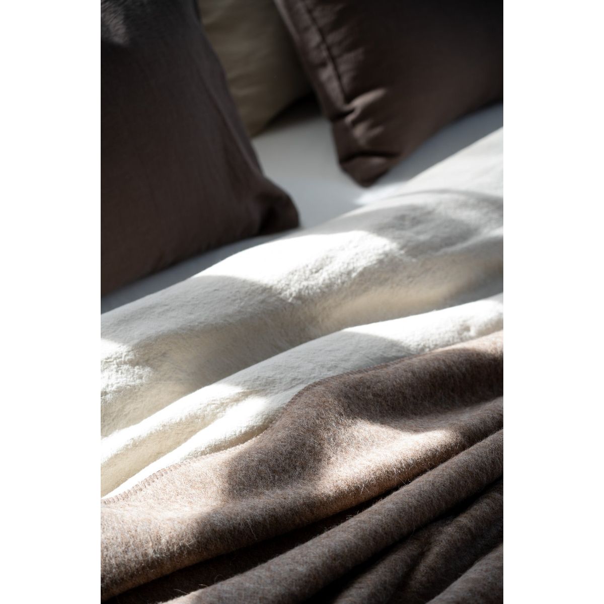 Close-up of a textured blanket with pillows in the background