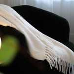 White blanket draped over a dark green sofa with a blurred background