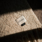 Close-up of a 'sömm' label on a textured fabric surface.