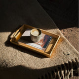 Wooden tray with a cup of coffee and book on a textured surface
