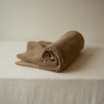 Rolled brown towel on a beige surface