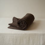 Rolled brown towel on a white surface with a neutral background