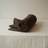 Rolled brown towel on a white surface with a neutral background