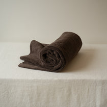 Rolled brown towel on a white surface with a neutral background