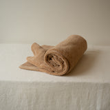 Rolled beige towel on a white surface with a neutral background
