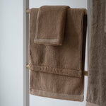 Brown towels hanging on a towel rack against a white background