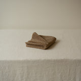 Folded brown towel on a beige surface
