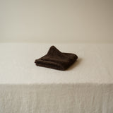 Folded brown towel on a white surface with a neutral background
