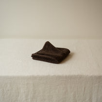 Folded brown towel on a white surface with a neutral background
