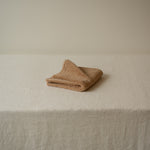 Folded beige towel on a textured surface with a neutral background