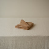 Folded beige towel on a textured surface with a neutral background