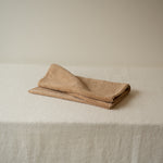 Folded beige towel on a textured white surface