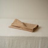 Folded beige towel on a textured white surface