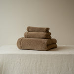 Stack of brown towels on a beige surface with a neutral background