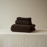 Stack of brown towels on a beige surface with a neutral background