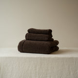 Stack of brown towels on a beige surface with a neutral background