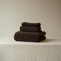 Stack of brown towels on a beige surface with a neutral background