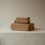 Stack of brown towels on a textured surface with a neutral background