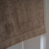 Brown towel hanging against a white wall