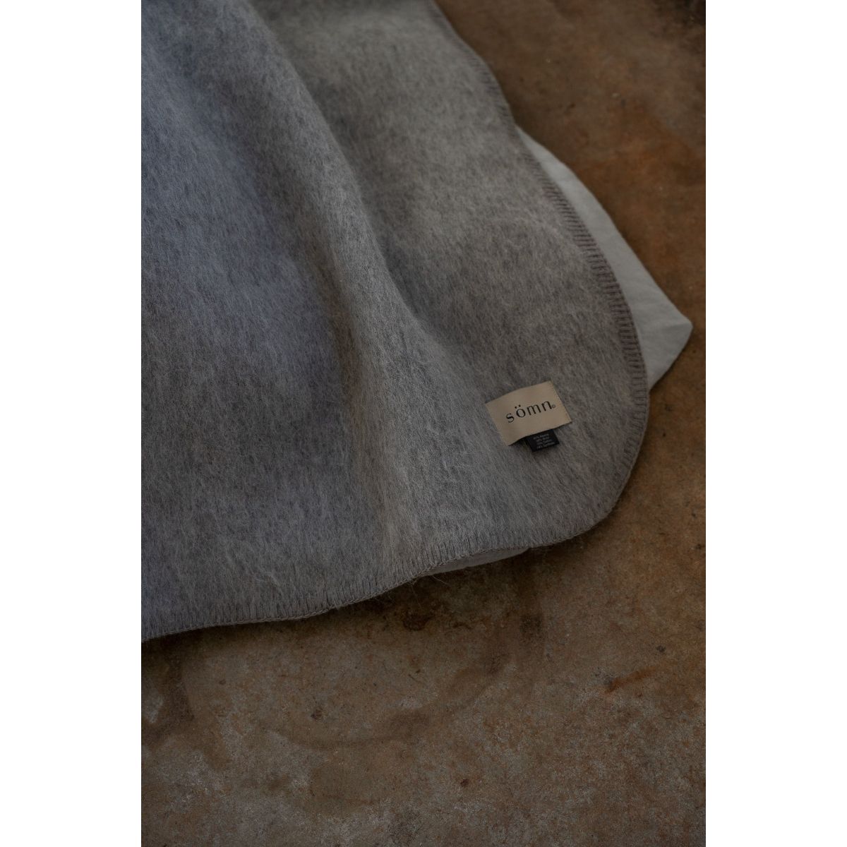 Gray blanket with a brand label on a textured surface