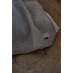Gray blanket with a brand label on a textured surface