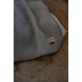 Gray blanket with a brand label on a textured surface