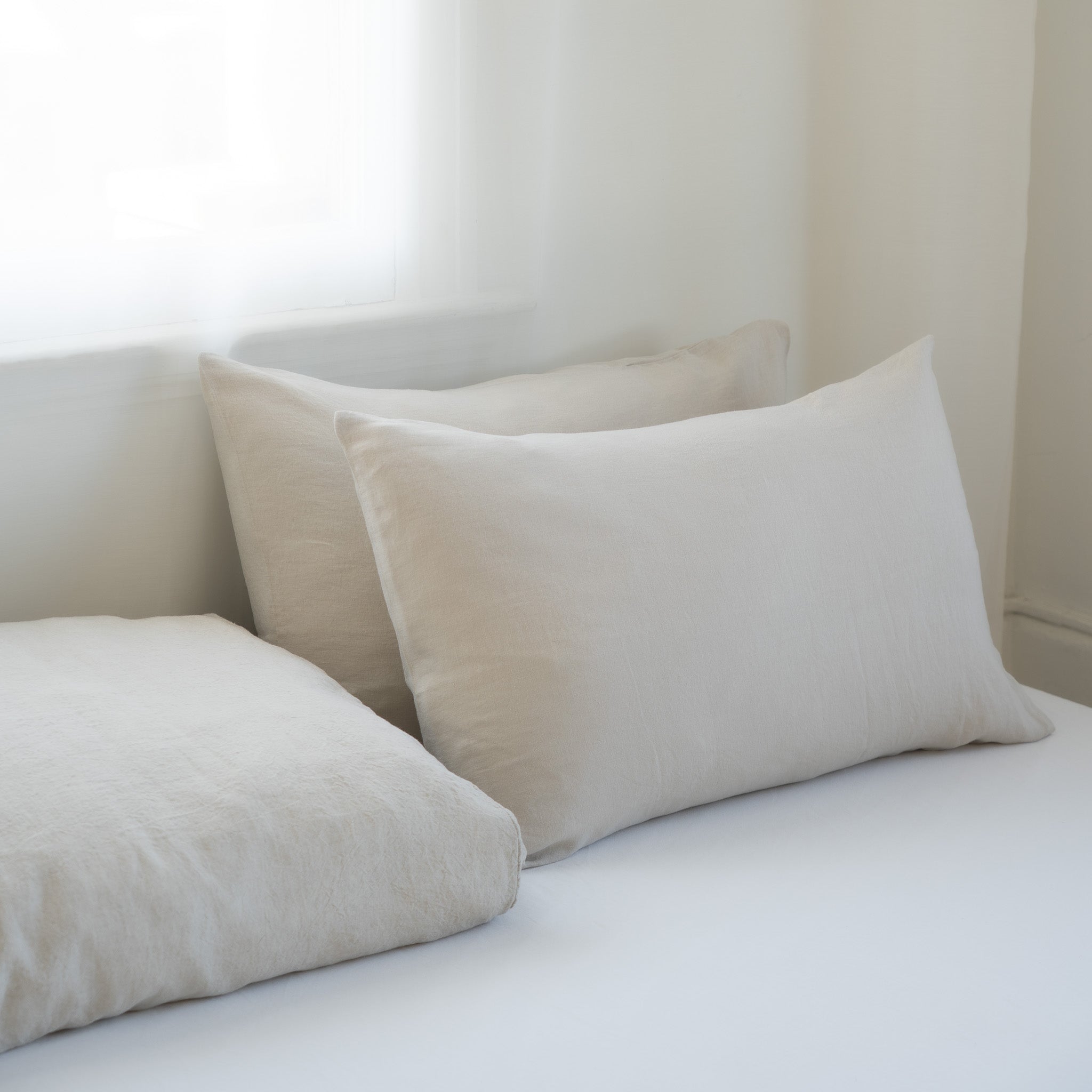 Beige pillows on a white bed against a neutral wall