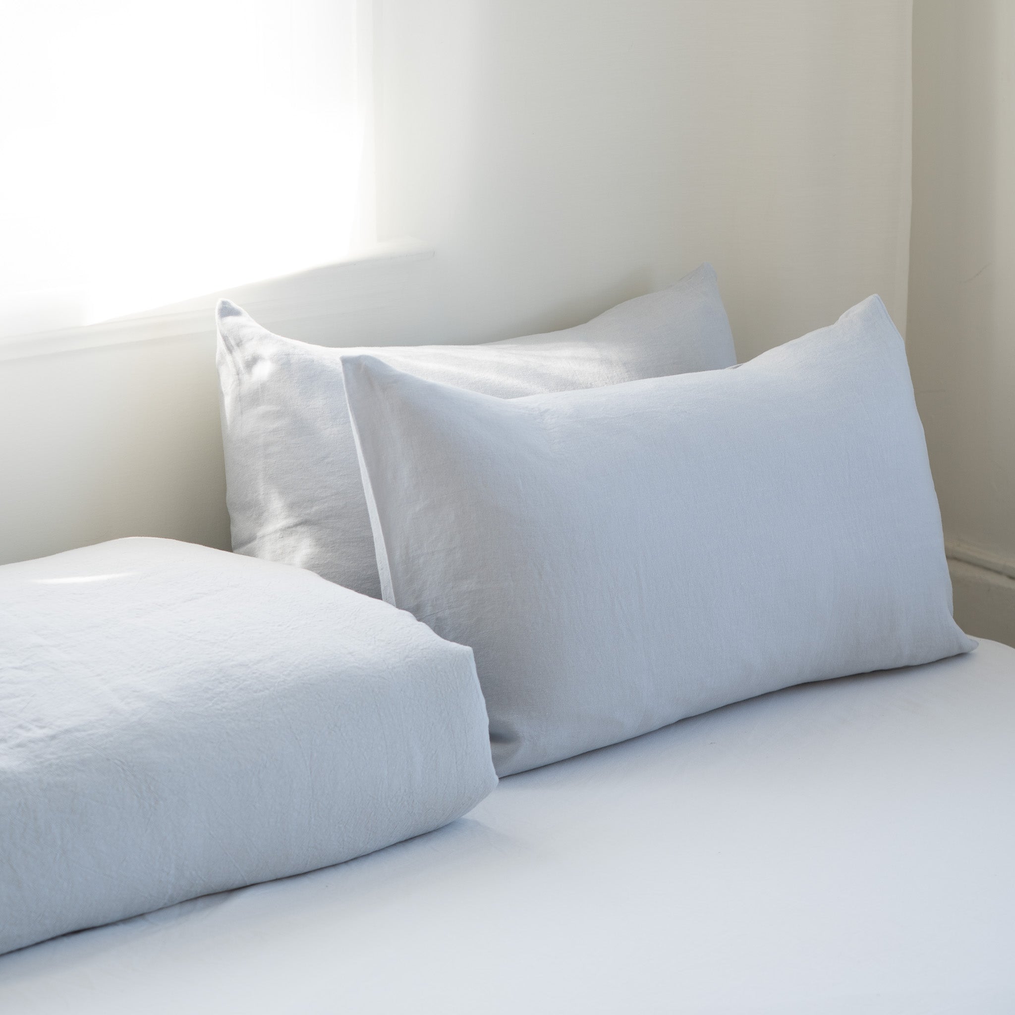 Light blue pillows on a bed against a neutral wall