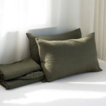Two green pillows on a white surface with a neutral background