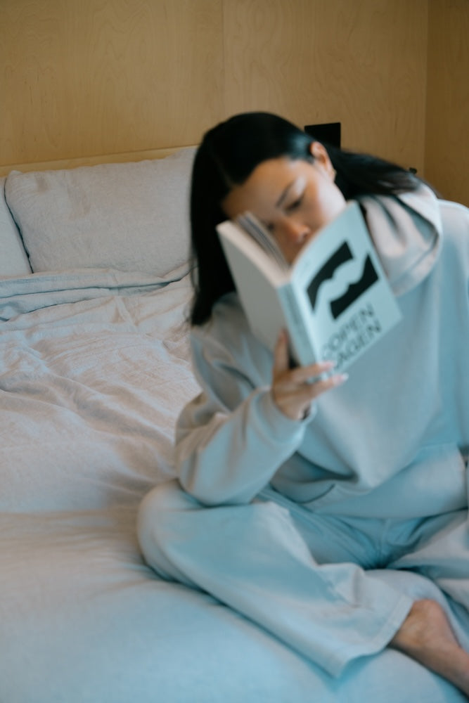 Woman reading a book on a bed in a cozy room