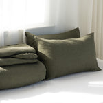 Green bedding set with pillows on a bed in a softly lit room.