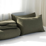 Green bedding set with pillows on a bed in a softly lit room.