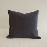 Dark gray pillow on a beige surface