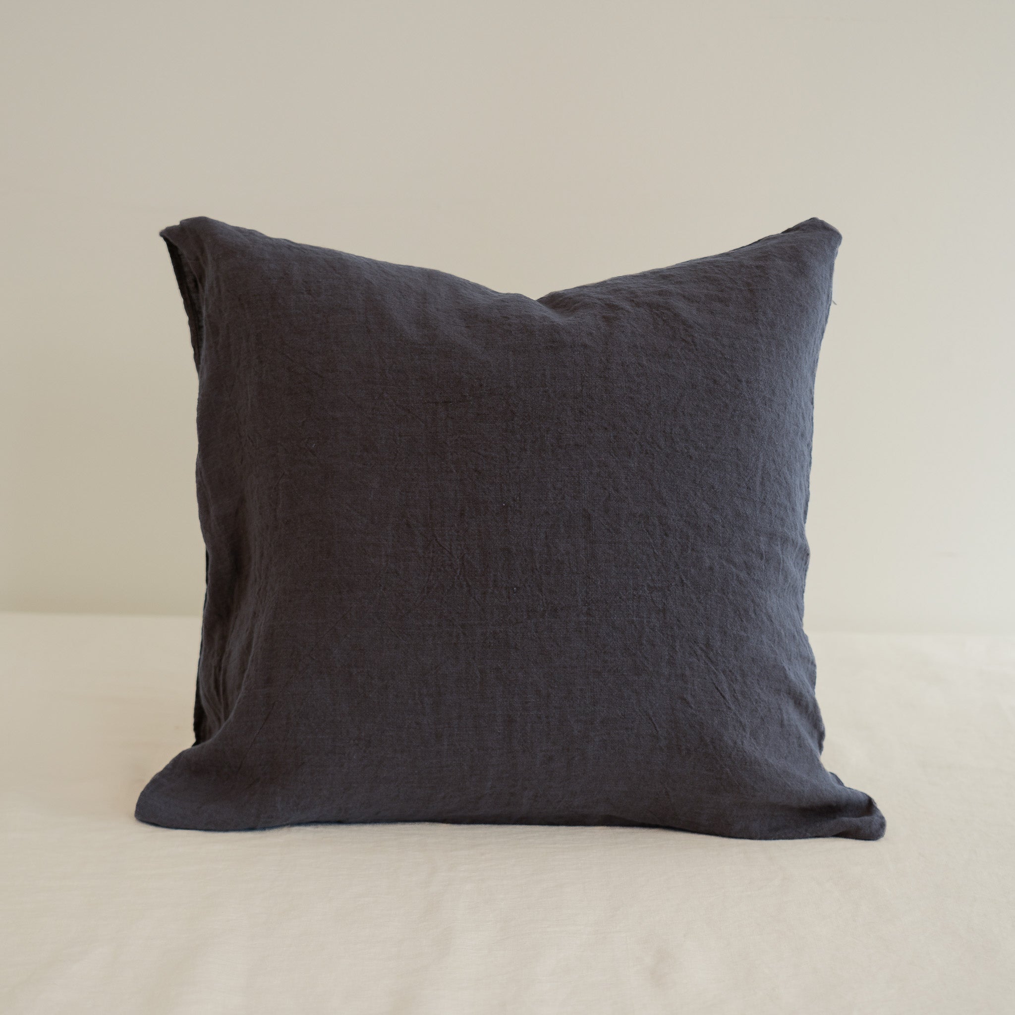Dark gray pillow on a beige surface