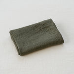 Folded dark green fabric on a light gray background