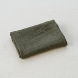 Folded dark green fabric on a light gray background